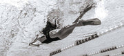 A lady swimming with fins and a kickboard in the pool