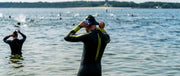 Man putting on swim cap in a triathlon by open water