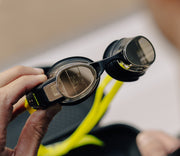 Swimmer adjusting his goggles equipped with digital displays, preparing for a swim.